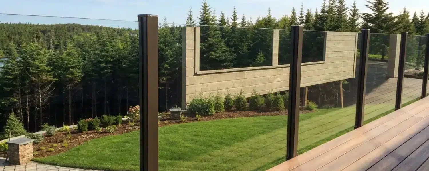 Bronze-post topless glass railing installed along a landscaped backyard deck