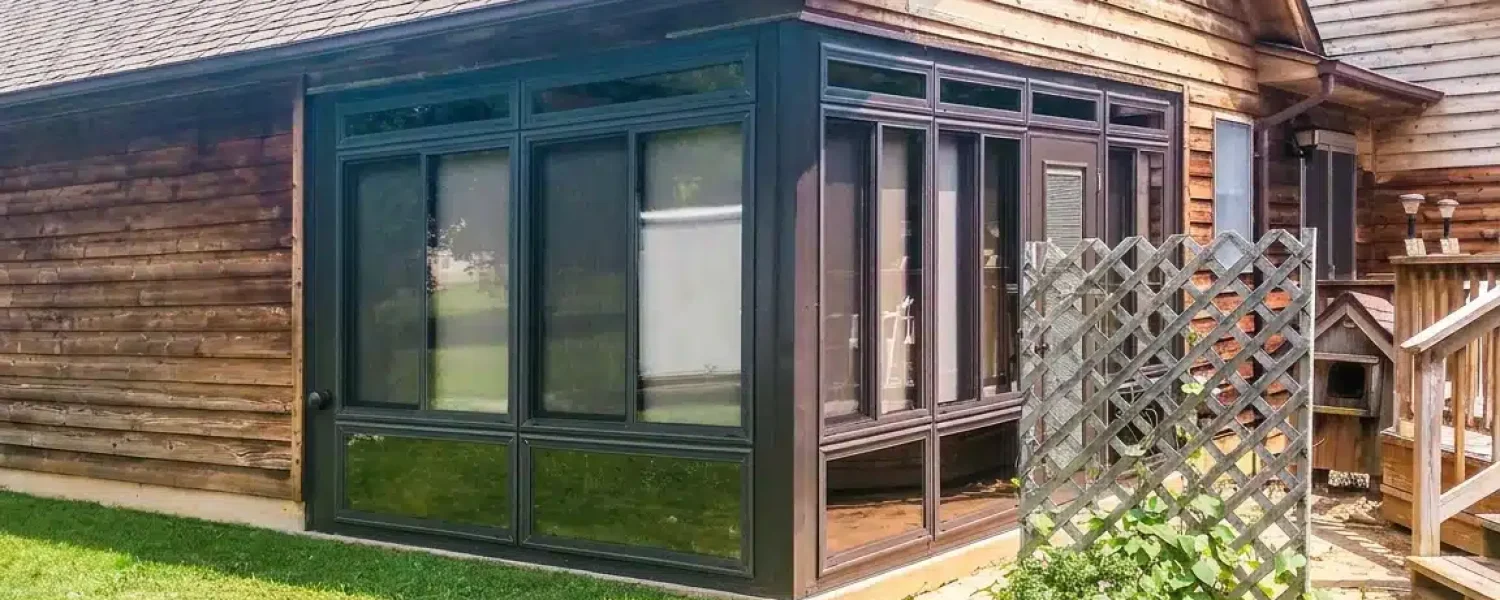 Glass porch enclosure attached to a wood-sided home