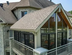 Enclosed porch with black-framed windows attached to a stone home